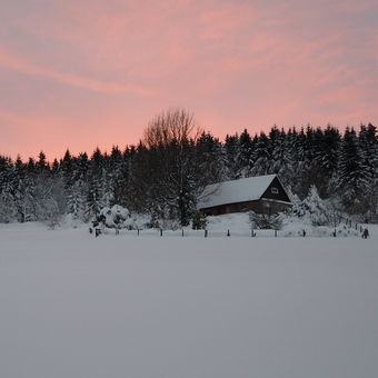 Opuštěná a zapadaná chata ve vrcholící zimě.